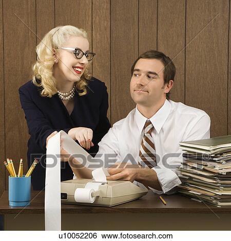 Stock Photograph - Mid-adult Caucasian male holding printout from calculator as Caucasian female points. . Fotosearch