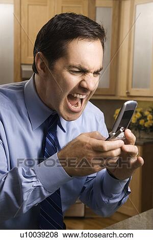 Mid-adult Caucasian male screaming at cell phone while standing in kitchen. View Large Photo Image Stock Photo - Mid-adult Caucasian male screaming at cell phone while standing in kitchen.. Fotosearch