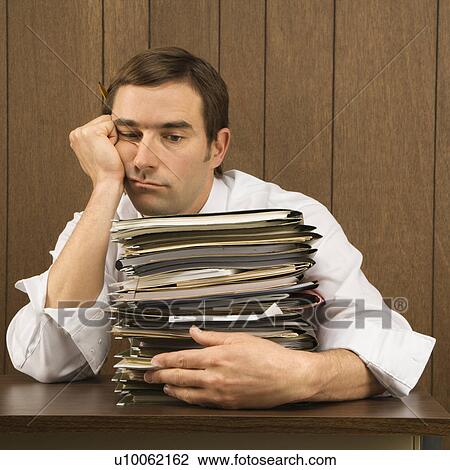 Mid-adult Caucasian male with overwhelmed face holding lots of paperwork View Large Photo Image Stock Image - Mid-adult Caucasian male with overwhelmed face holding lots of paperwork. Fotosearch