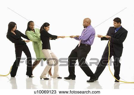 Stock Image - Multi-ethnic businessmen playing tug of war against businesswomen.. Fotosearch