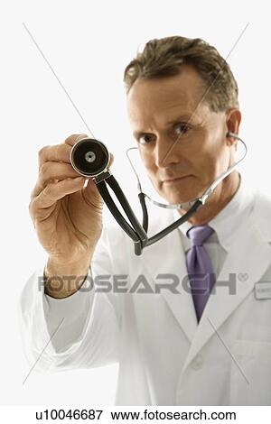 Stock Photo - Studio shot of a mid-adult Caucasian male doctor holding out stethoscope.. Fotosearch