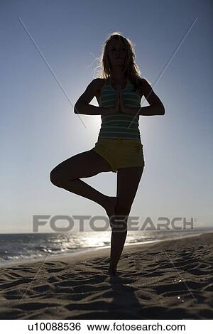 Stock Photograph - Woman on beach doing yoga. Fotosearch