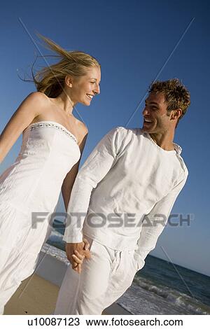 Stock Image - Couple walking on beach. Fotosearch