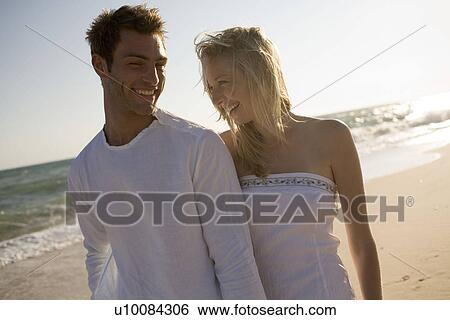 Stock Photograph - Couple walking on beach. Fotosearch