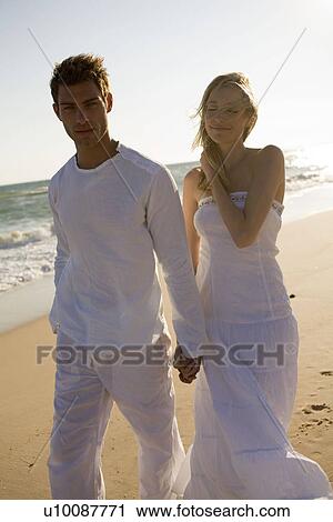 Stock Image - Couple walking on beach. Fotosearch