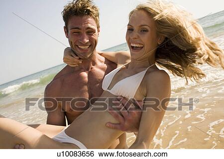Stock Photograph - Young couple on beach. Fotosearch
