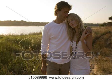 Stock Photograph - Young couple walking by lake. Fotosearch