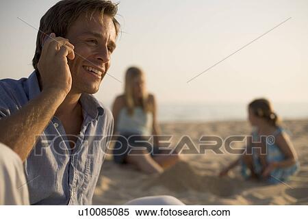 Family on beach, man on phone View Large Photo Image Stock Photography - Family on beach, man on phone. Fotosearch