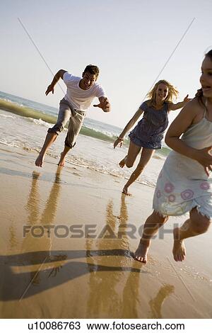 Stock Image - Family on beach playing together. Fotosearch