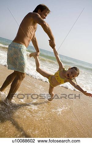 Stock Image - Family on beach playing together. Fotosearch