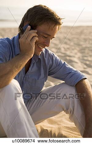 Picture - Man on phone on beach. Fotosearch