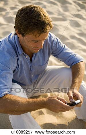 Stock Photo - Man on phone on beach. Fotosearch