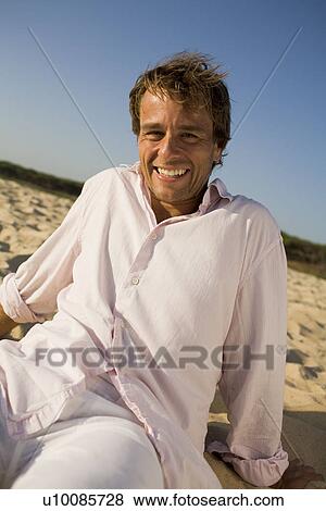 Stock Photo - Man sitting on beach. Fotosearch