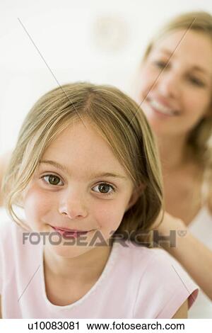 Stock Image - Mother and daughter, brushing hair. Fotosearch
