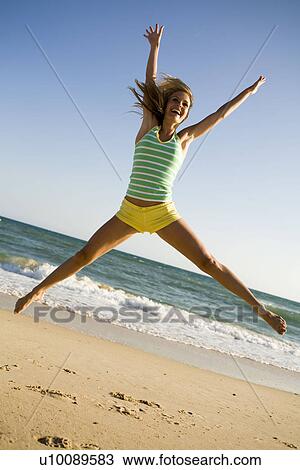 Woman doing star jump on beach View Large Photo Image Stock Image - Woman doing star jump on beach. Fotosearch