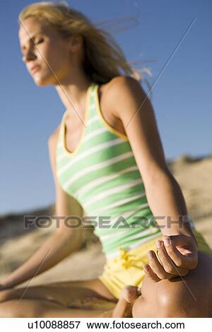 Stock Photo - Woman on beach doing yoga. Fotosearch