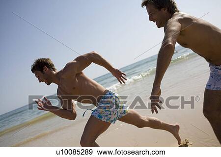 Stock Photo - Two men running on beach. Fotosearch