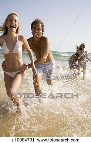 Stock Image - Two young couples on beach. Fotosearch