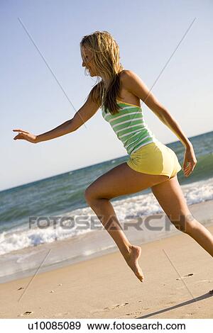 Stock Photo - Woman on beach running. Fotosearch