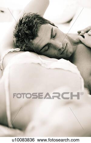 Stock Photograph - Young couple lying on bed. Fotosearch