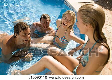 Stock Image - Young couples by pool. Fotosearch