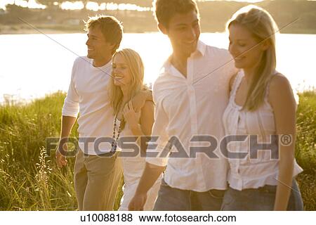 Stock Photo - Young couples walking by lake. Fotosearch