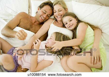 Picture - Family laying in bed. Fotosearch