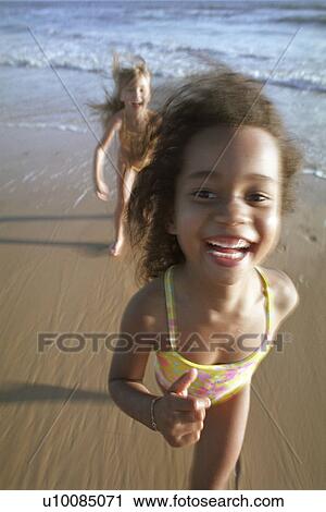 Stock Image - Two girls running on the beach. Fotosearch