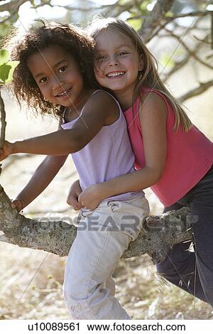 Two girls sitting in tree View Large Photo Image Stock Image - Two girls sitting in tree. Fotosearch