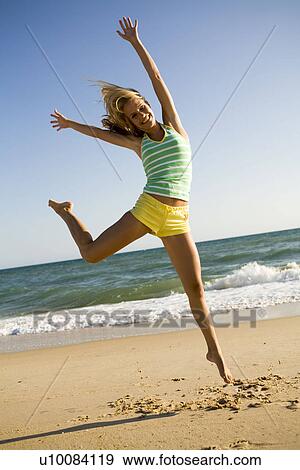 Woman doing star jump on beach View Large Photo Image Stock Photo - Woman doing star jump on beach. Fotosearch