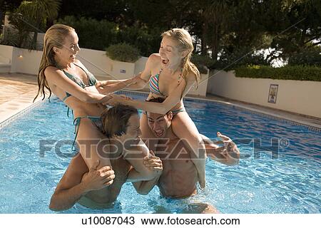Stock Image - Young couples play fighting in pool. Fotosearch