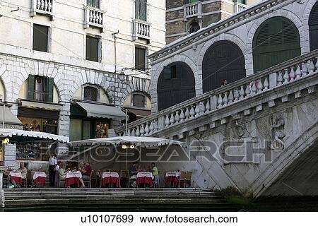 Umbrella covered red and pink clothed tables at canal side with Rialto Bridge as backdrop View Large Photo Image Stock Photo - Umbrella covered red and pink clothed tables at canal side with Rialto Bridge as backdrop. Fotosearch