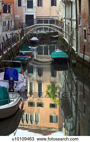 Quiet canal, bridge in distance, building reflections, boats moored at side View Large Photo Image Stock Image - Quiet canal, bridge in distance, building reflections, boats moored at side. Fotosearch