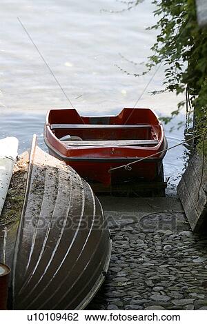 Stock Image - Rowboats out of water and waters edge on stone slipway Lago di Como Italy. Fotosearch