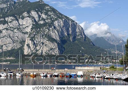 Stock Image - Sailboats in harbour Lago di Como Italy mountain beyond . Fotosearch