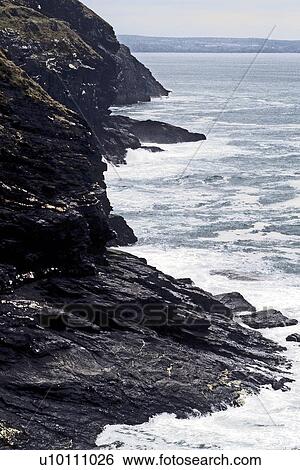 Stock Photograph - Coastline view with overcast sky and waves near Tintagel Devon England UK. Fotosearch
