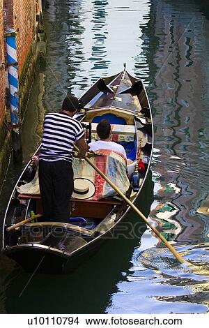 Gondolier in Gondola with passengers on quiet canal - reflections in water View Large Photo Image Picture - Gondolier in Gondola with passengers on quiet canal - reflections in water. Fotosearch
