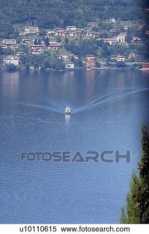Stock Photography - Looking down on Lago di Como Italy Car ferry on lake, hills and town in background. Fotosearch