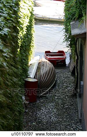 Stock Photo - Osuccio-beached boats in alleyway vy lake. Fotosearch
