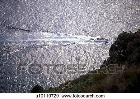 Stock Photo - Powerboat with wake from above, sunlit water. Fotosearch