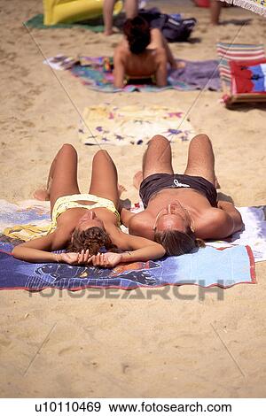 Stock Photo - Sunbathers on towels and sand beach Italy. Fotosearch