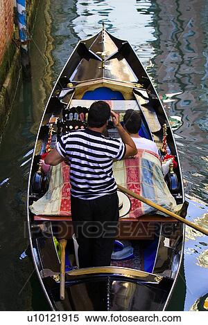 Stock Photography - Gondolier in Gondola with passengers on quiet canal. Fotosearch