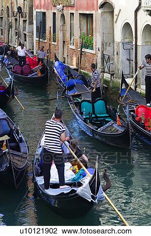 Stock Image - Gondoliers on busy narrow canal. Fotosearch