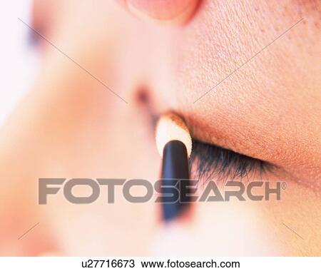 Stock Image - A Woman Applying Brown-Colored Eye Shadow, Differential Focus. Fotosearch