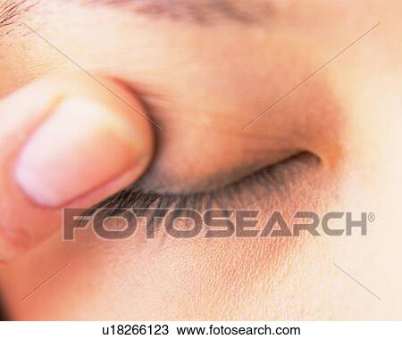 Stock Image - A Woman Applying Eye Shadow with a Finger, Front View, Differential Focus. Fotosearch