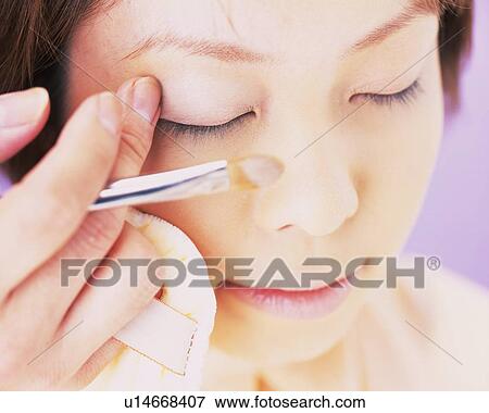 Stock Photo - A Woman Applying Eye Shadow with a Finger, Differential Focus. Fotosearch