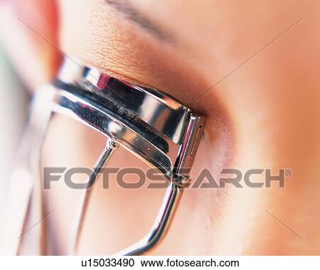 Stock Image - A Woman Applying Eyelash Curler, Differential Focus. Fotosearch