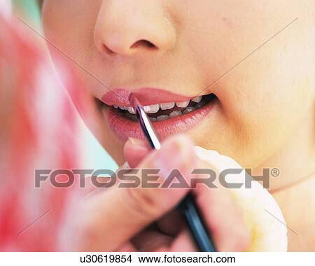Picture - A Woman Applying Pink Colored Lip Gloss, Differential Focus. Fotosearch