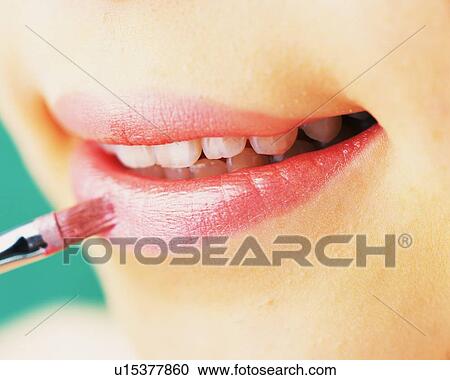 Stock Image - A Woman Applying Pink Colored Lip Gloss, Differential Focus. Fotosearch