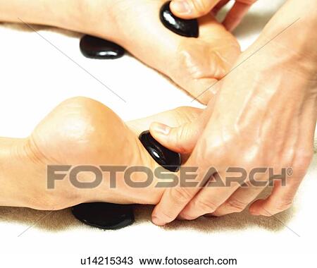 Stock Image - Aesthetician Who Pushes Woman's Foot With Stones. Fotosearch